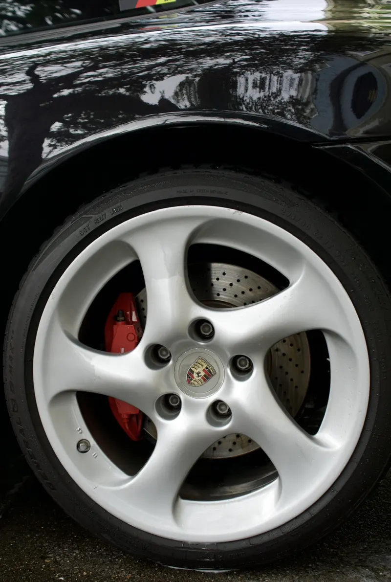 After: the same silver Porsche wheel cleaned, with its red brake caliper visible